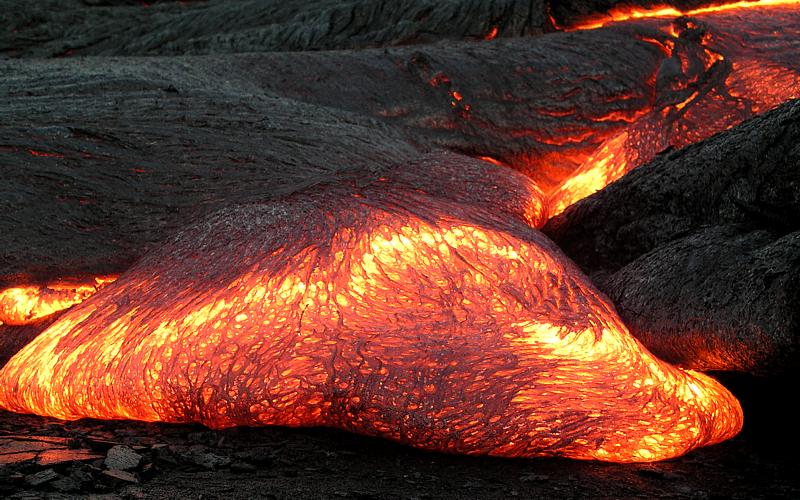 Deze Pahoehoe lava toont een glad, golvend en touwachtig oppervlak. Het ontstaat bij een langzame, relatief vloeibare stroming van basaltische lava met een lage viscositeit en hogere temperatuur. Onder deze harde korst blijft vloeibare lava vaak stromen, waardoor zachte, vloeiende vormen ontstaan.